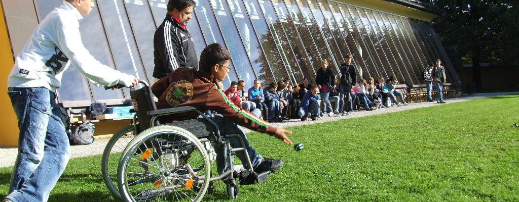 KInd im Rollstuhl spielt Boule